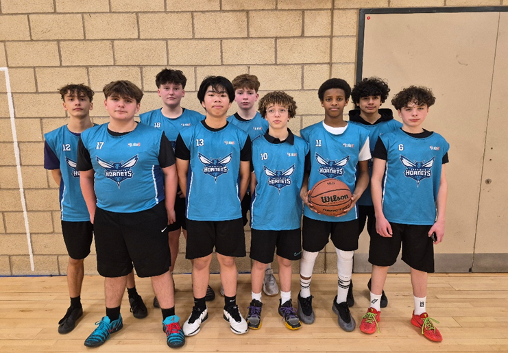 A group of boys in blue jerseys ione holding a basketball