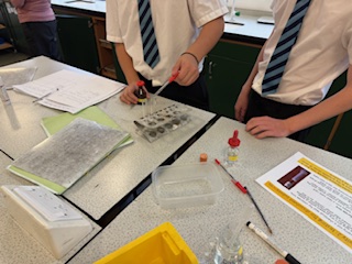 two students at a desk carrying out an experiment
