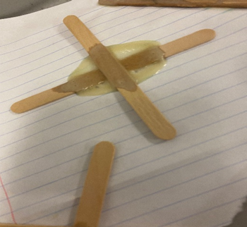 two lolly sticks on a piece of paper