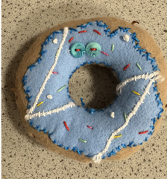 A blue donut with a hole in the center made from fabric