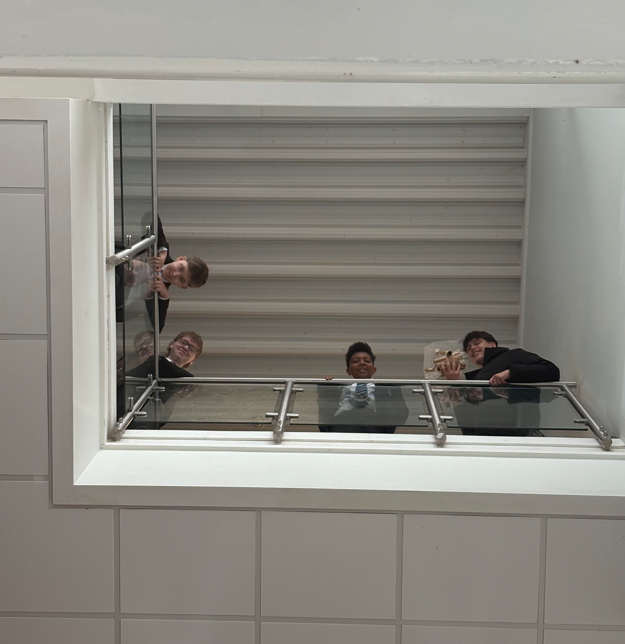 four students standing on a high level to drop their egg bundles 