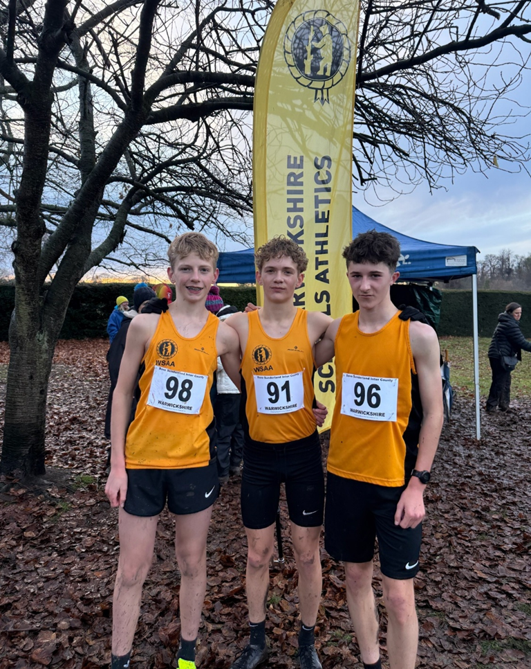 three students in running vests at a cross country event 