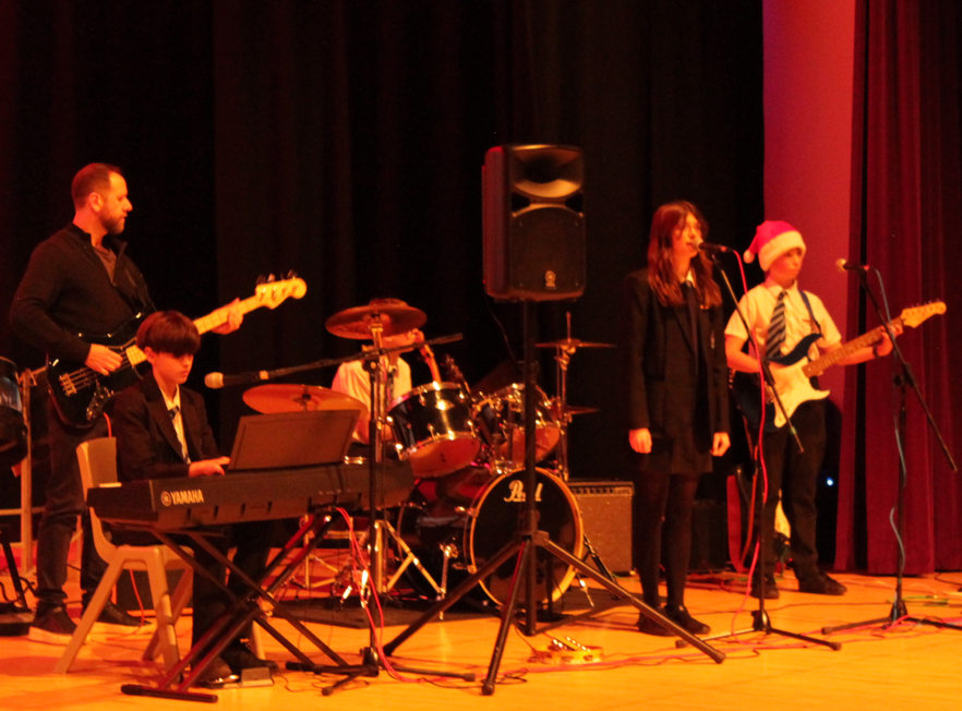 four students and their teacher performing at the music concert