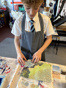 A person in an apron making a press print