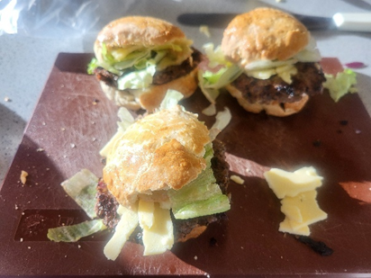 three burgers on a wooden surface