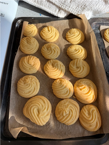 Photograph showing freshly baked round cookies with a swirled pattern on a parchment-lined baking tray - Viennese whirls