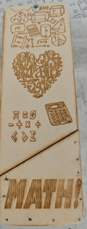 Wooden bookmark engraved with various mathematical symbols and illustrations, including Venn diagrams, graphs, calculator, geometric shapes, and algebraic expressions. Central heart shape formed by numbers and symbols, with "MATH!" prominently displayed at bottom. 