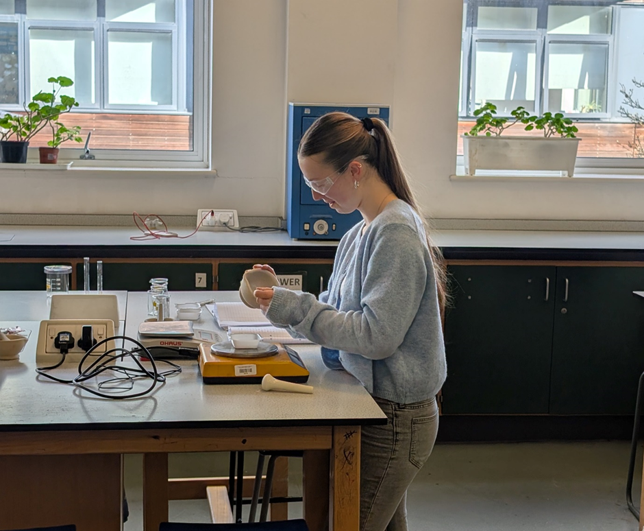 student conducting an experiment in a lab using a pestle and mortar