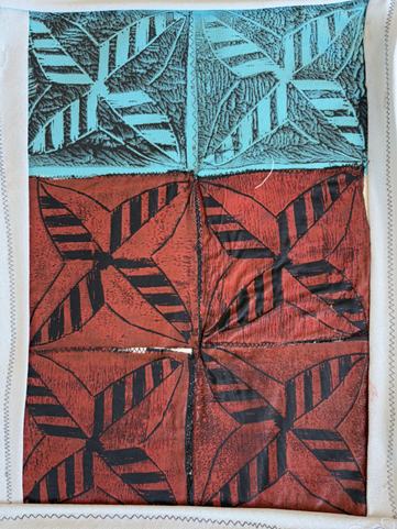 Photograph of a textile featuring a geometric leaf pattern divided into six sections, with two top sections in turquoise and four bottom sections in reddish-brown. Each section contains a stylised leaf with diagonal stripes, outlined in black, creating a bold contrast against the coloured backgrounds.