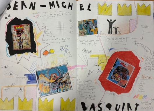 A photograph of an open scrapbook or art journal spread featuring mixed media elements, including colourful drawings, handwritten notes, and pasted images. The spread includes bold text labels "BASQUIAT" and "JEAN-MICHEL," yellow banner shapes, and various abstract shapes and sketches, highlighting an artistic tribute or study of Jean-Michel Basquiat's work.