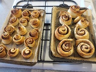 Two  trays of cinnamon rolls on a hob