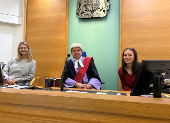 two students sitting in a court with a judge