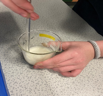 A person mixing a liquid in a glass
