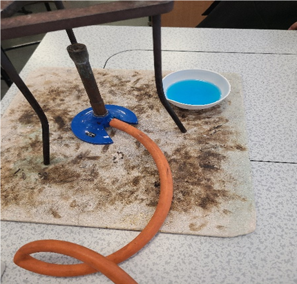 a bowl of blue water next to a bunsen burner