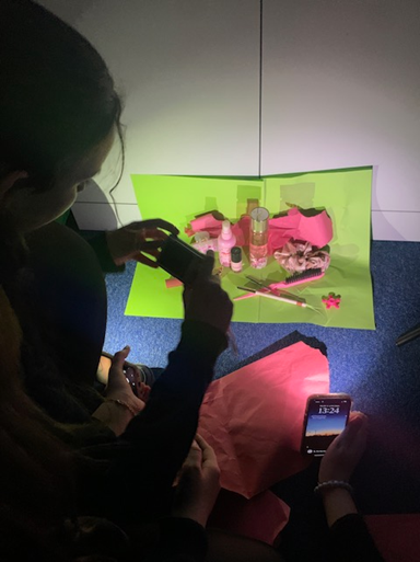 two people taking a picture of pink items against a green backgrounda child