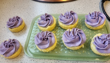 A group of cupcakes with purple frosting on a green tray