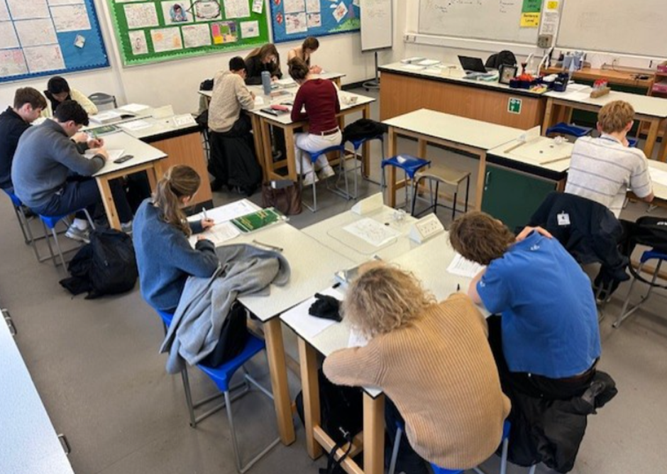 A group of people sitting at tables in a classroom