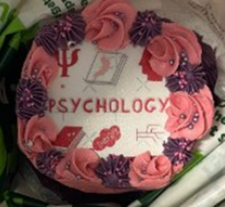 A cake decorated with pink and purple flowers and the word psychology at the bake sale