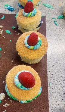 A group of cupcakes with blue frosting and raspberries on top