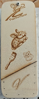 Photograph of a rectangular wooden block with engraved designs including a clock, a rabbit, a torch, a small animal face, and a stylised letter "V," 