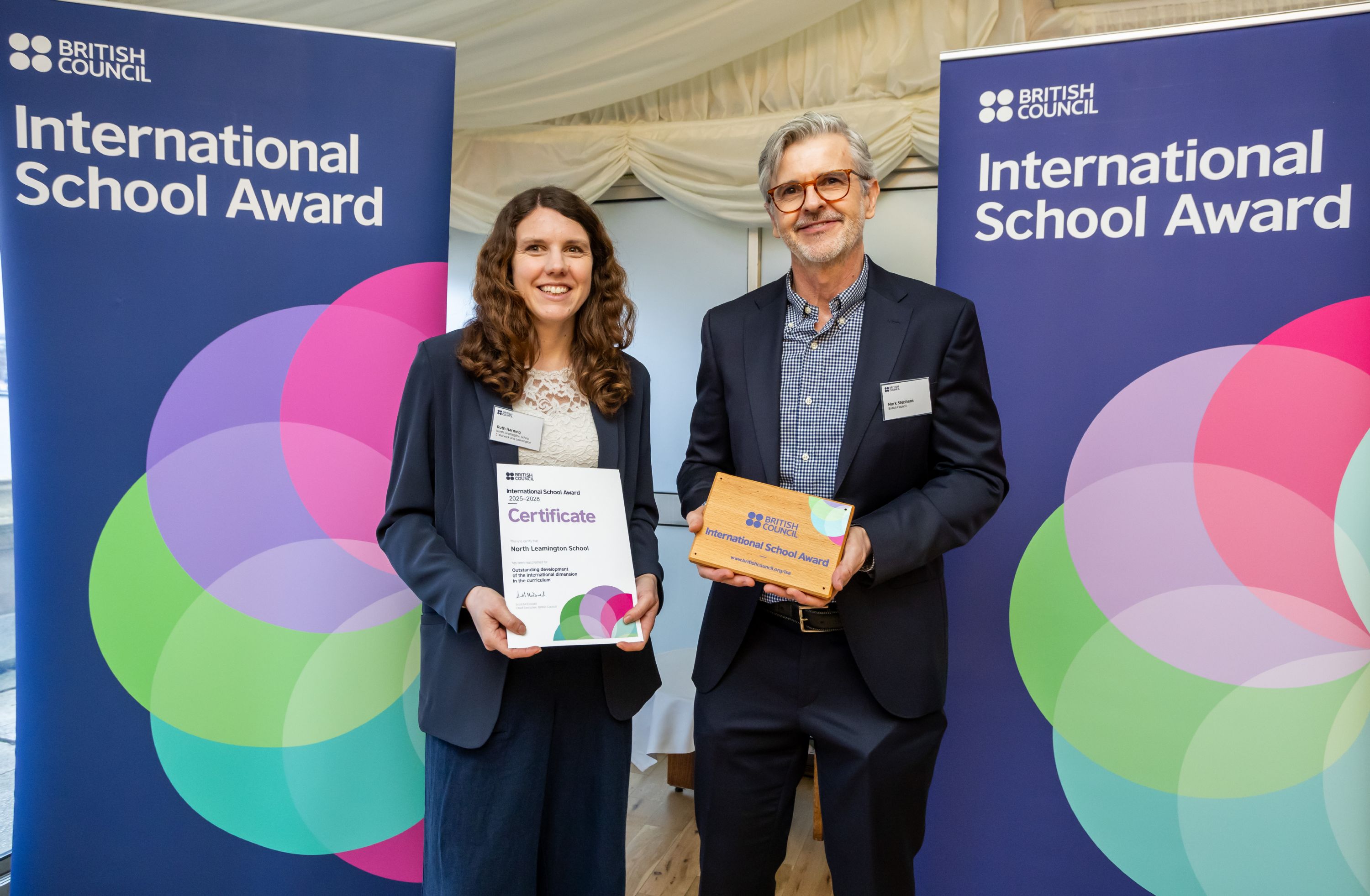 two people standing in from of a screen with an award