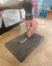 A person using a hammer to press a piece of metal
