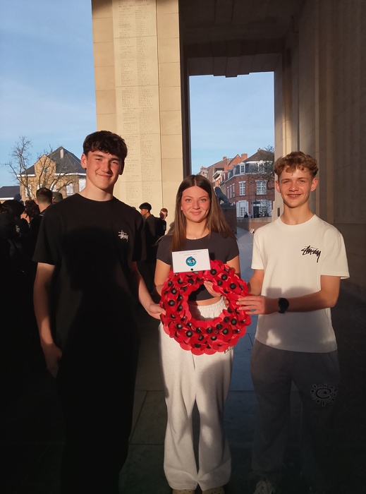 three studnets at Menin Gate with a wreath of poppies to lay 