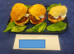 A plate of three burgers in rolls and salad leaves