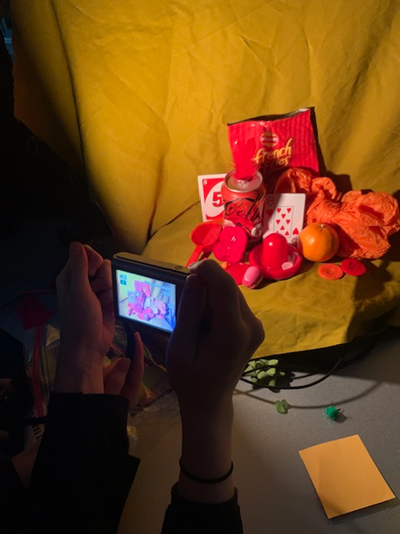 A person taking a picture of a  display of red and orange objects
