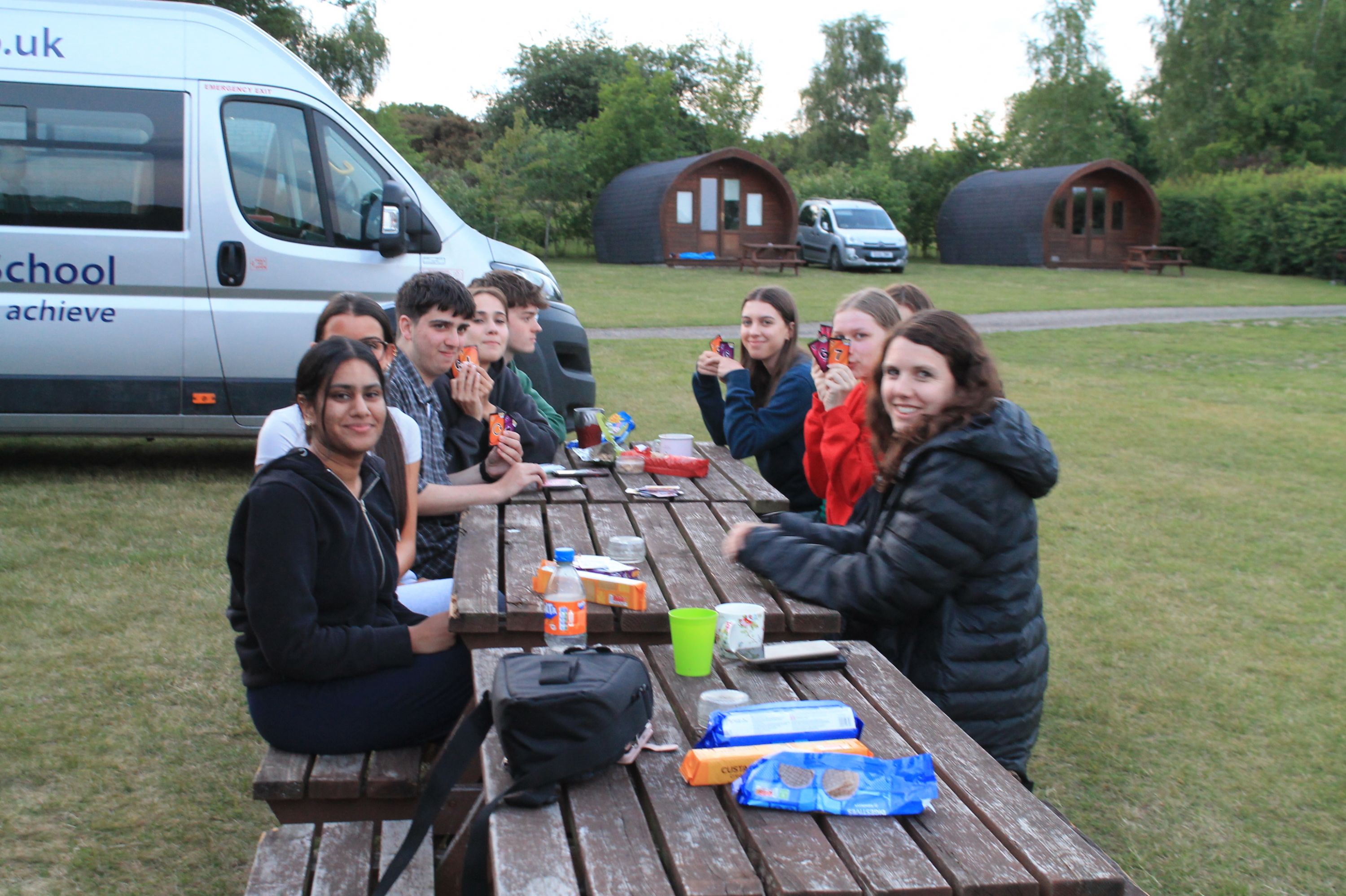 seven studenst and tehri teacher at the glamping pods eating lunch