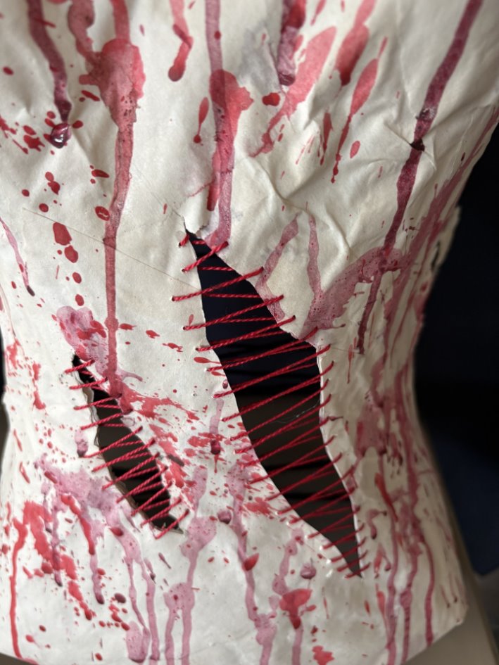 ​​A white paper with red threads and holes