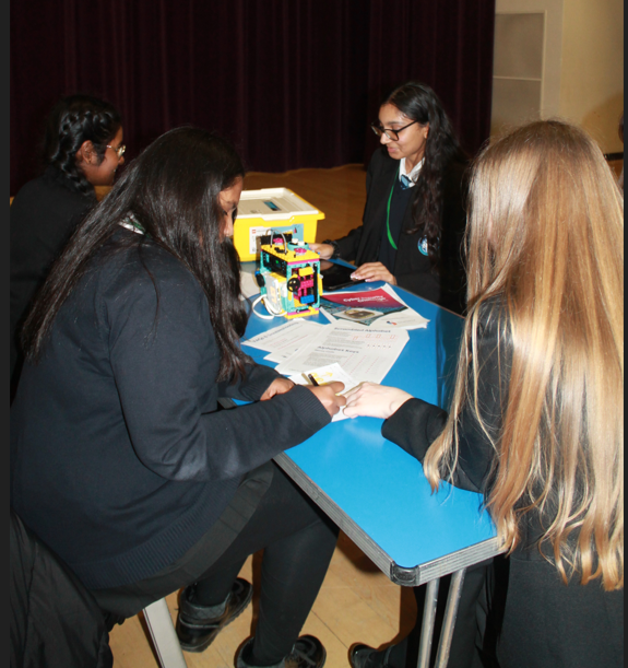 four students sitting at a table making their model