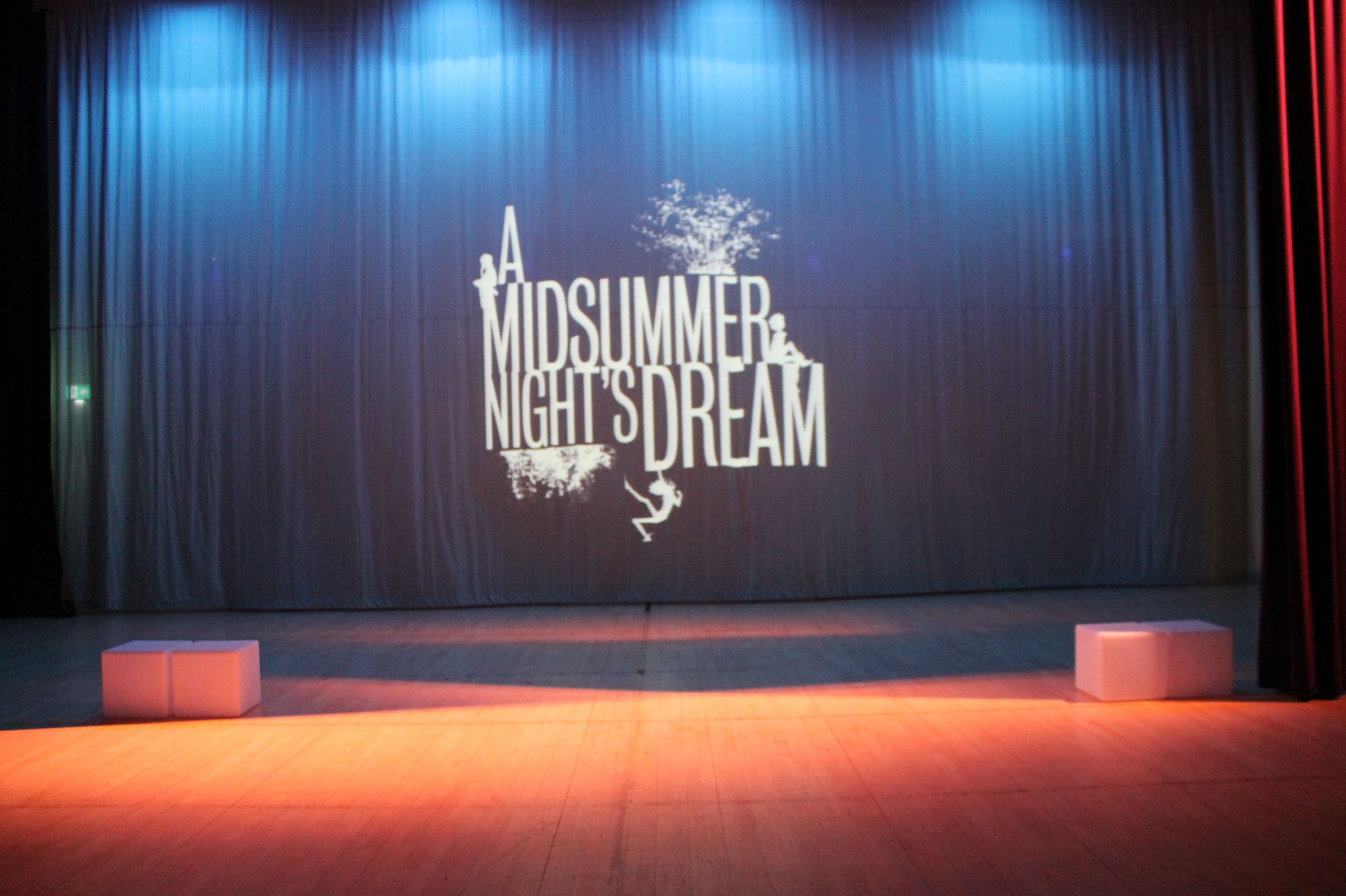 the stage lit with blue and orange lights and the title of the production  