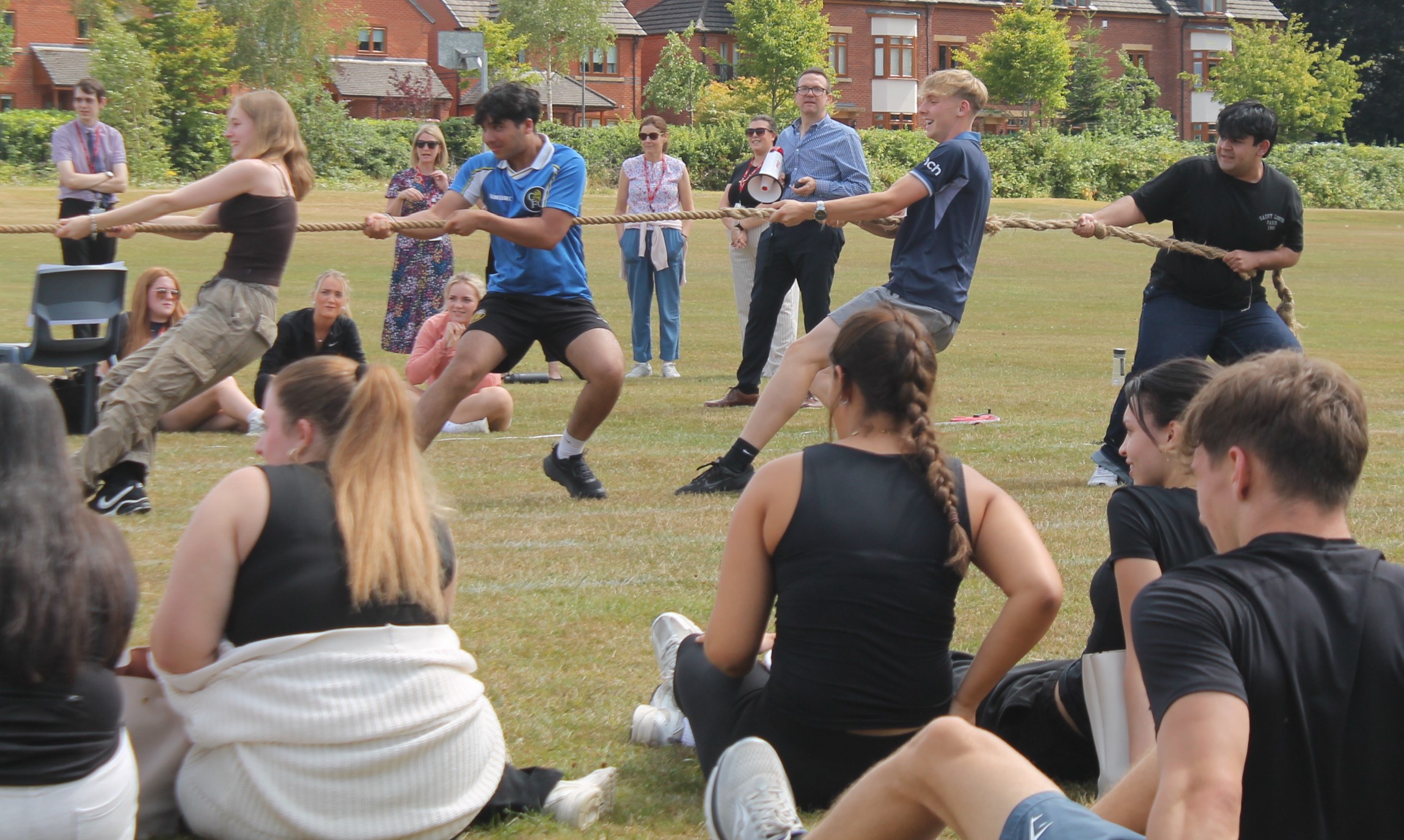four students ina tug of war with other students watching