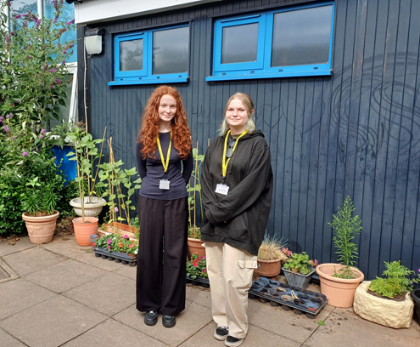 two NLS students standing outside the entrance to Telford Junior School
