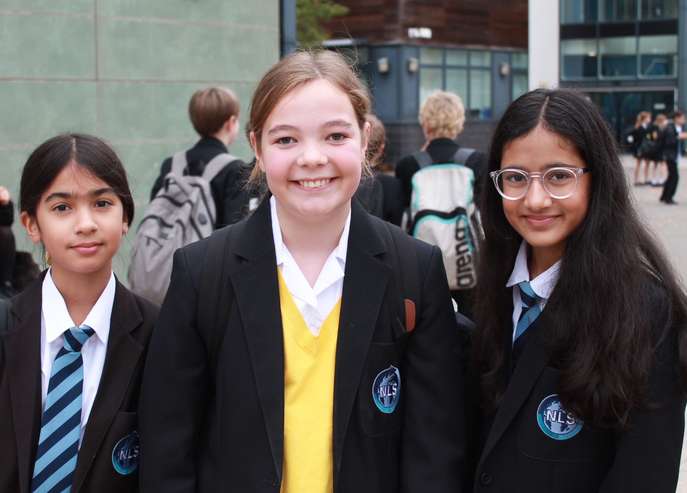 three girls with the one in middle wearing a  yellow jumper