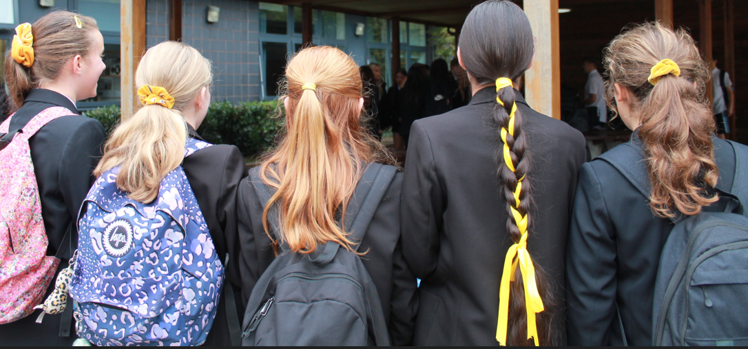 five girls all wearing a yellow hair accessory 