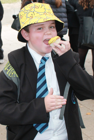 a students wearing a yellow hat eating a cake