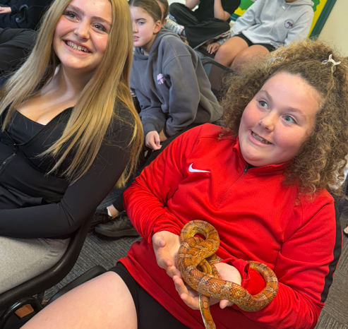 a student holding a snake and a child smiling