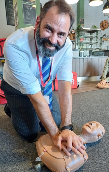 A person kneeling on the floor with a dummy doing CPR