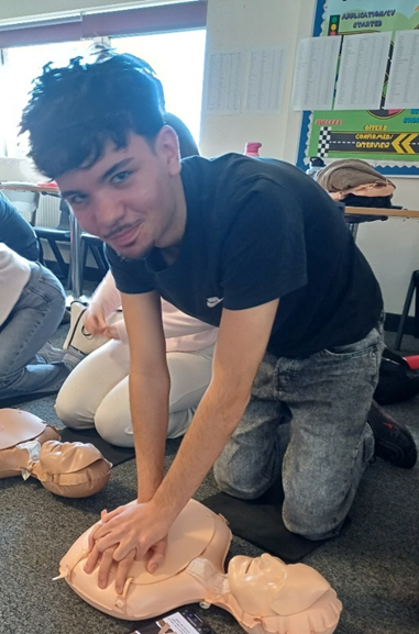 A person kneeling on the floor with a dummy doing CPR