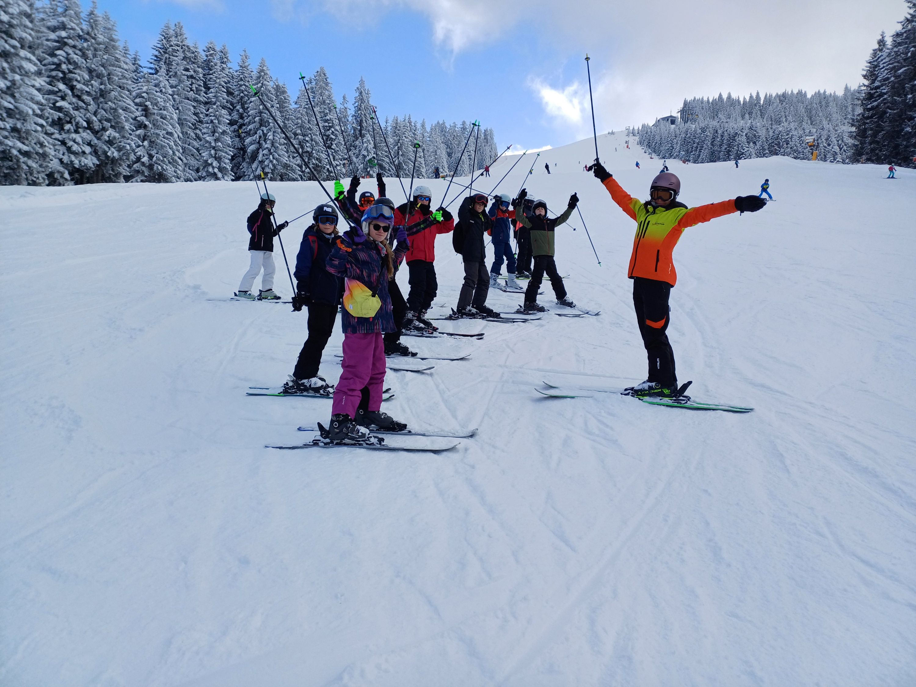 A group of NLS skiers on a ski slope standing with their poles in the air 