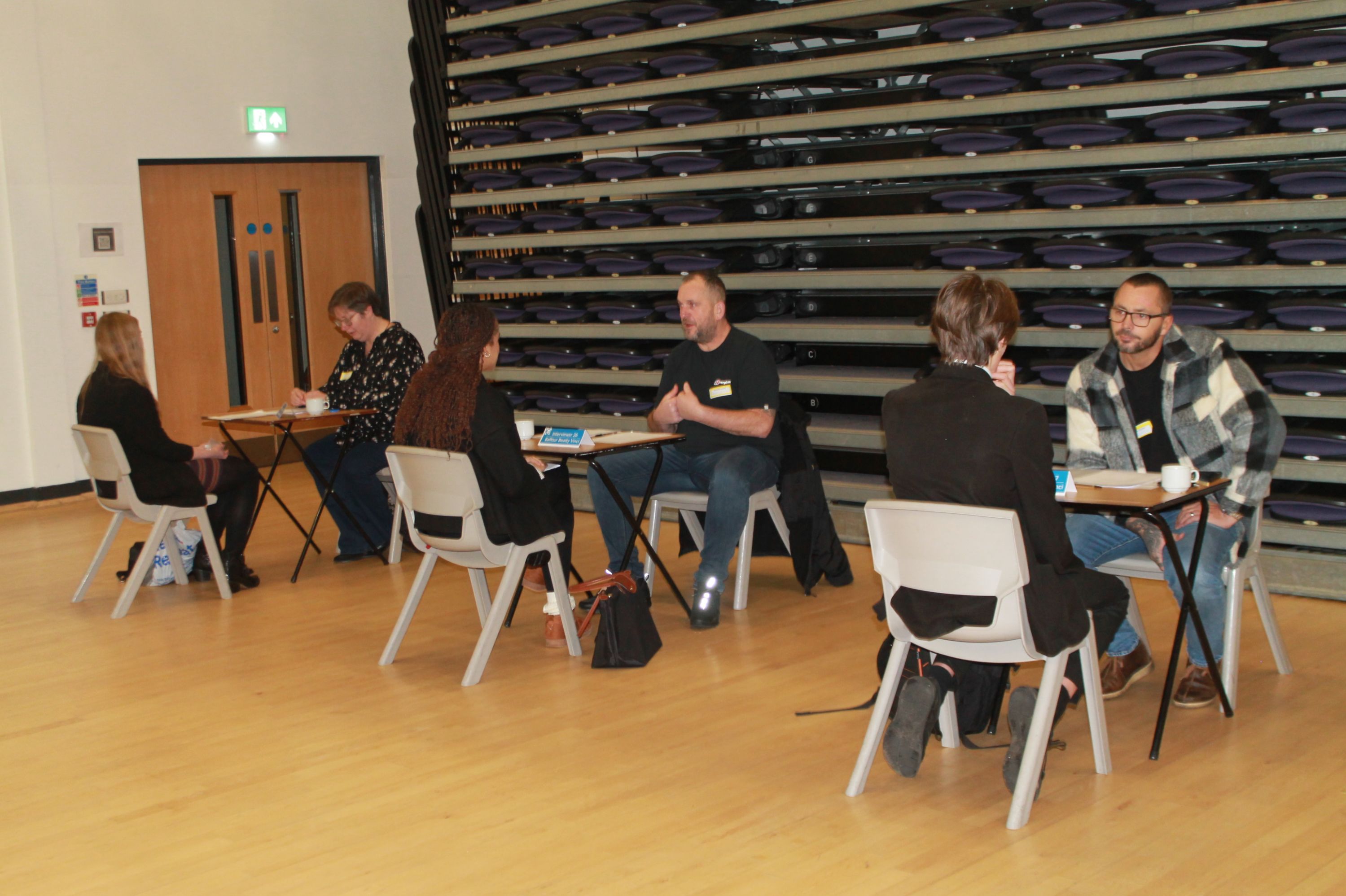 three students sitting at desks being interviewed