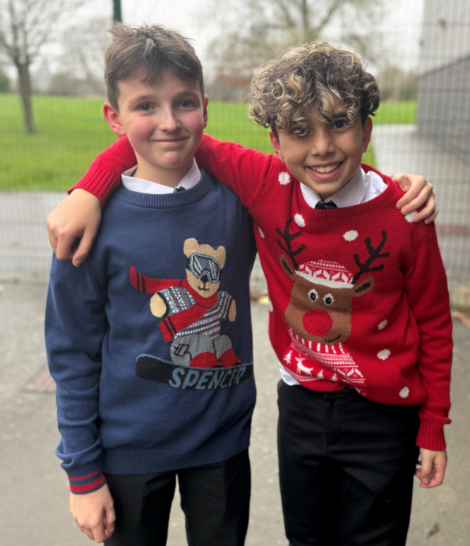 Two boys with their arms over each others' shoulders wearing Christmas jumpers