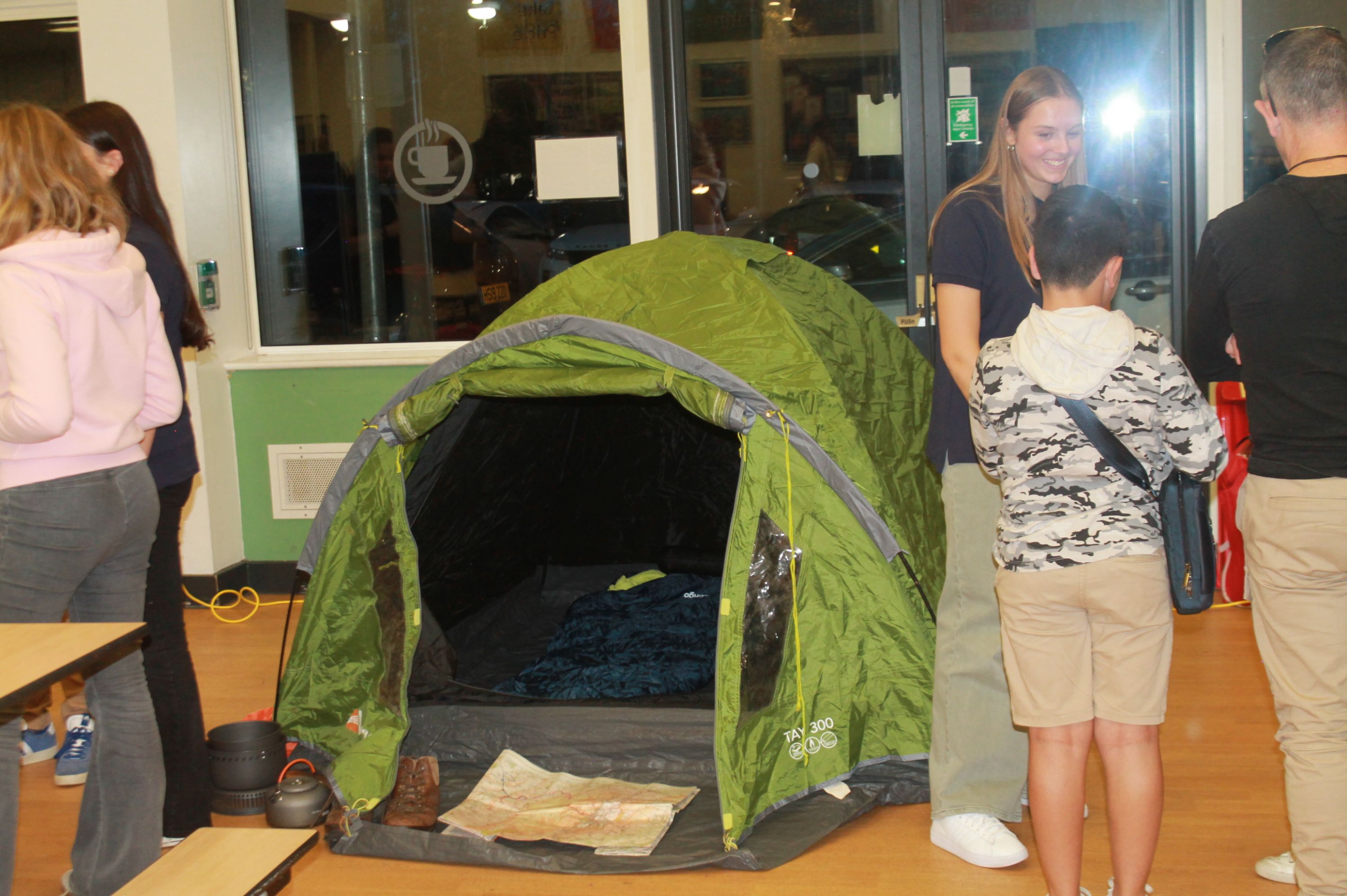 a student talking about DofE and a tent and equipment on dispaly. map, walking boot, sleeping bag 